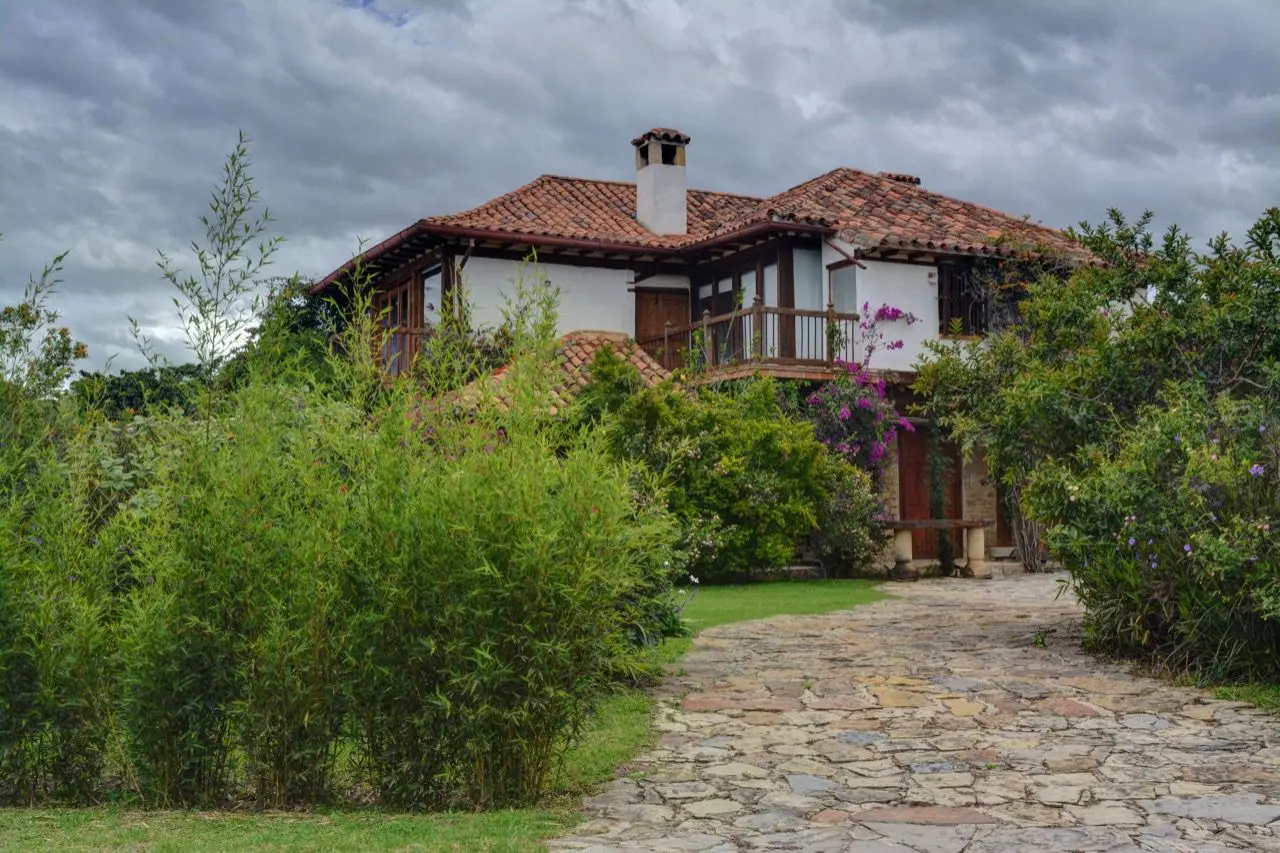 Das weiße koloniale Landhaus Casa Antares mit Ziegeldach, blühendem Garten und einem Steinweg