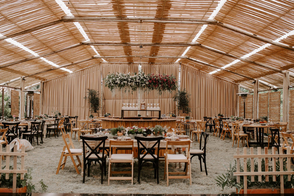 Die Pergola der Casa Antares mit gedeckten Holztischen, Bambusdach und Blumenschmuck